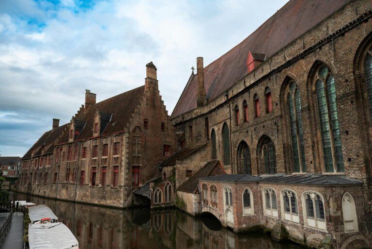 Canal medieval de Brujas con casas de ladrillo rojo reflejadas en el agua al atardecer