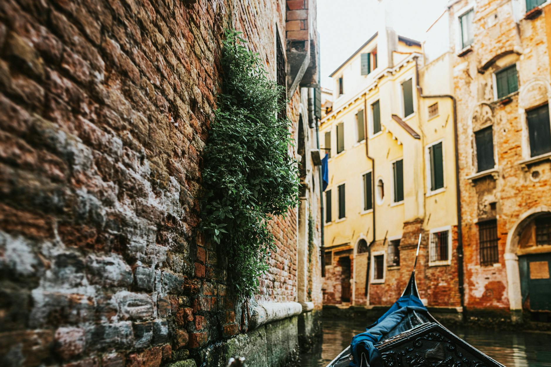 Canal estrecho de Venecia al amanecer con barcas y edificios reflejados en el agua