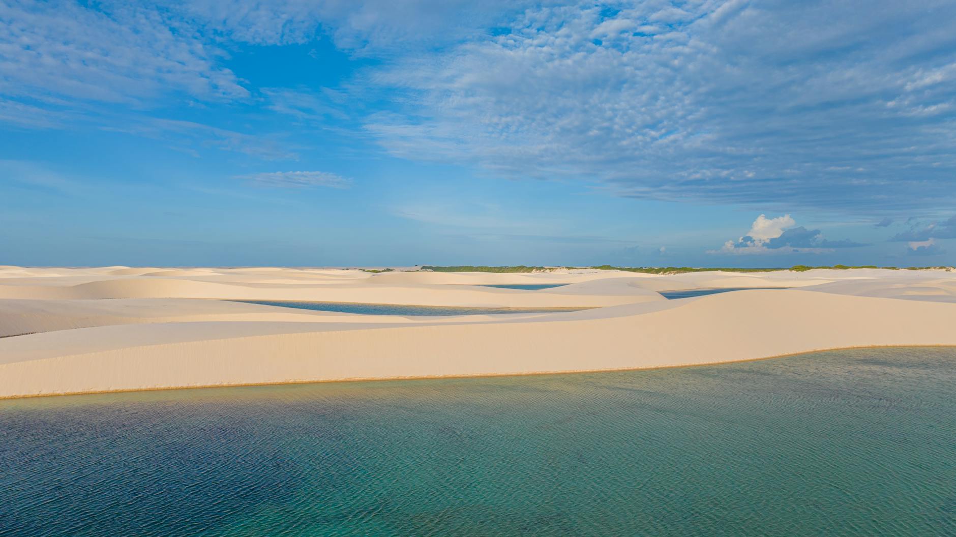 Laguna de agua dulce turquesa rodeada de dunas blancas en Lençóis Maranhenses