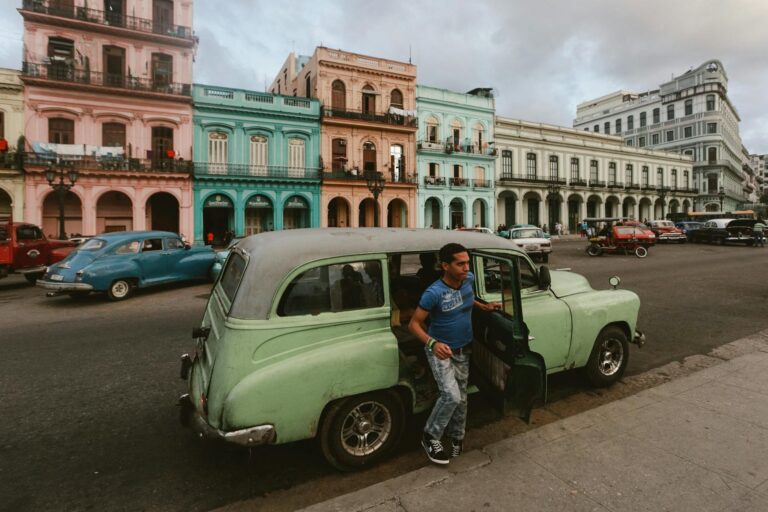 Coche clásico americano de color azul circulando por el Malecón de La Habana al atardecer