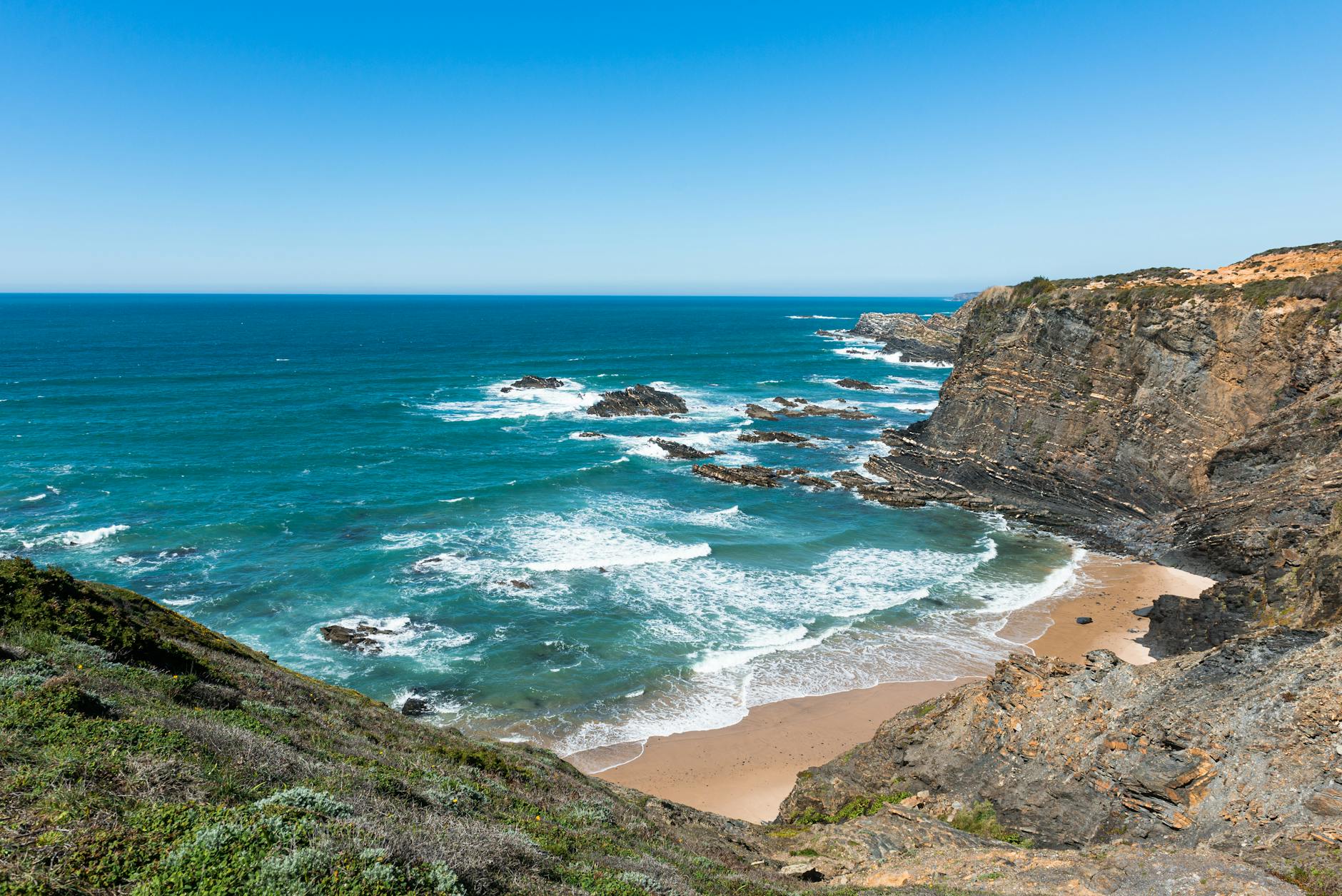 Acantilados rojizos de la Costa Vicentina con el océano Atlántico al fondo durante el atardecer