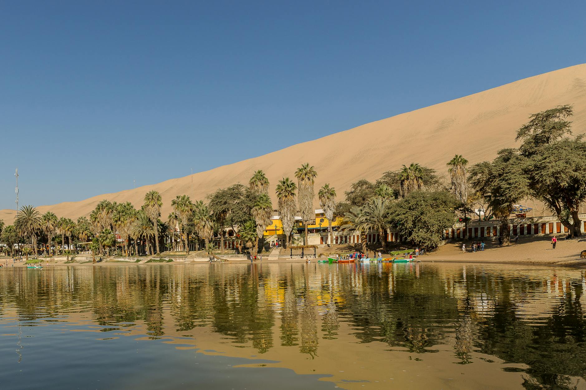 Persona practicando sandboarding en las dunas gigantes de Huacachina al atardecer