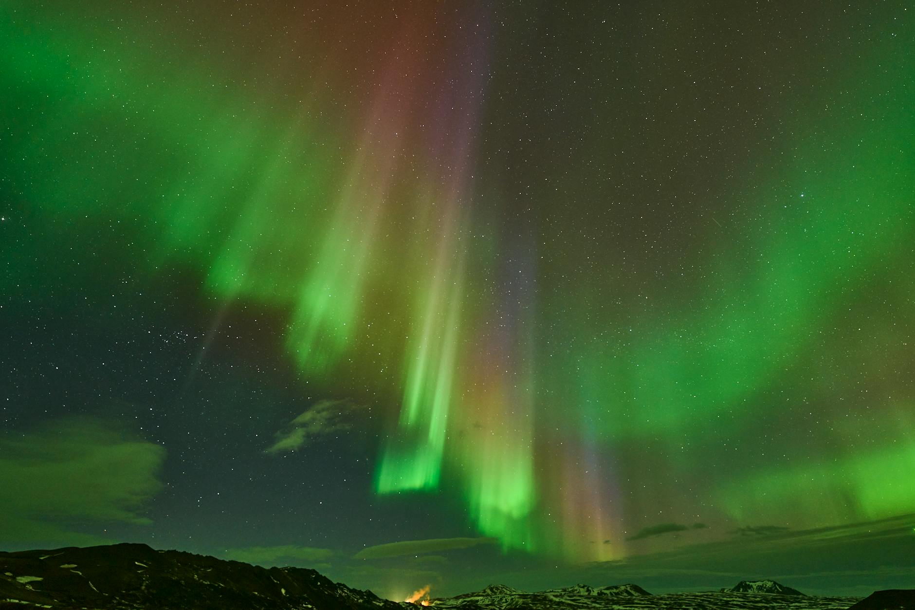 Auroras boreales de colores verdes y morados iluminando el cielo nocturno de Islandia sobre la carretera Ring Road
