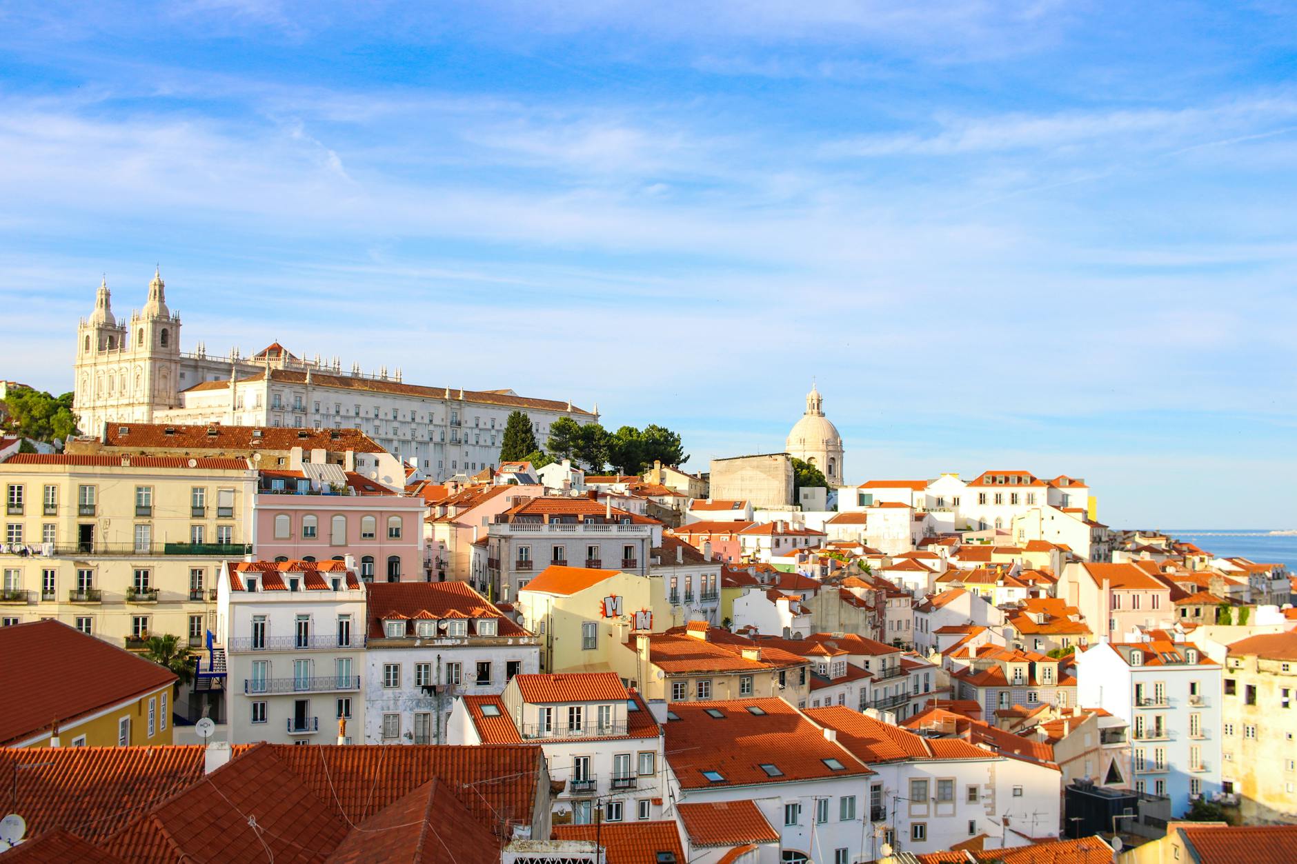 Vistas panorámicas desde el mirador de Alfama en Lisboa con tejados naranjas y el río Tajo al fondo