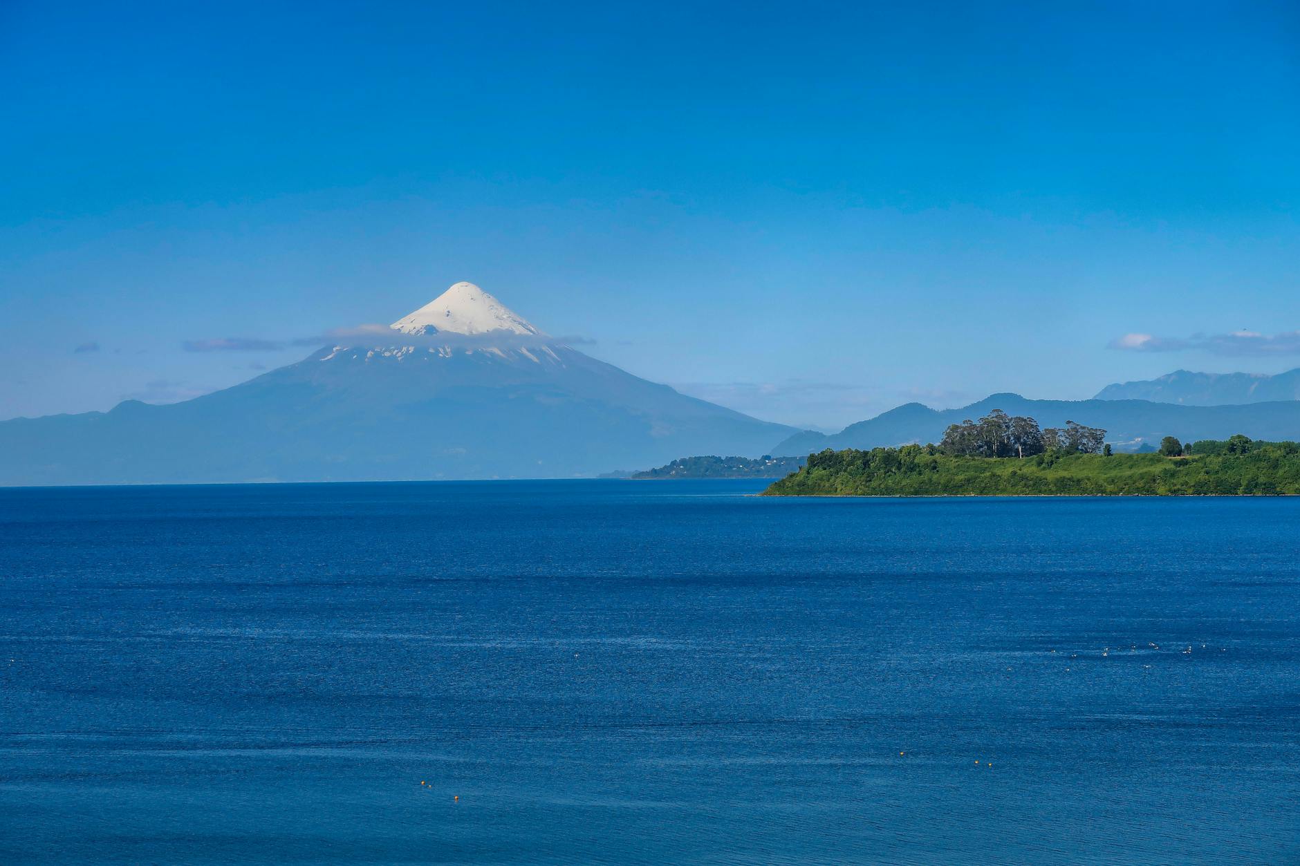 Persona practicando kayak en el lago Villarrica con el volcán al fondo