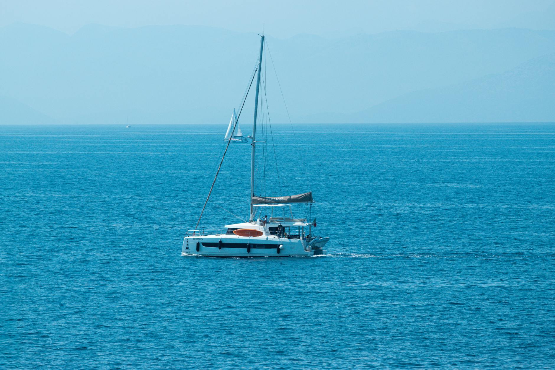Velero surcando el mar turquesa de las Islas Jónicas con Corfú al fondo