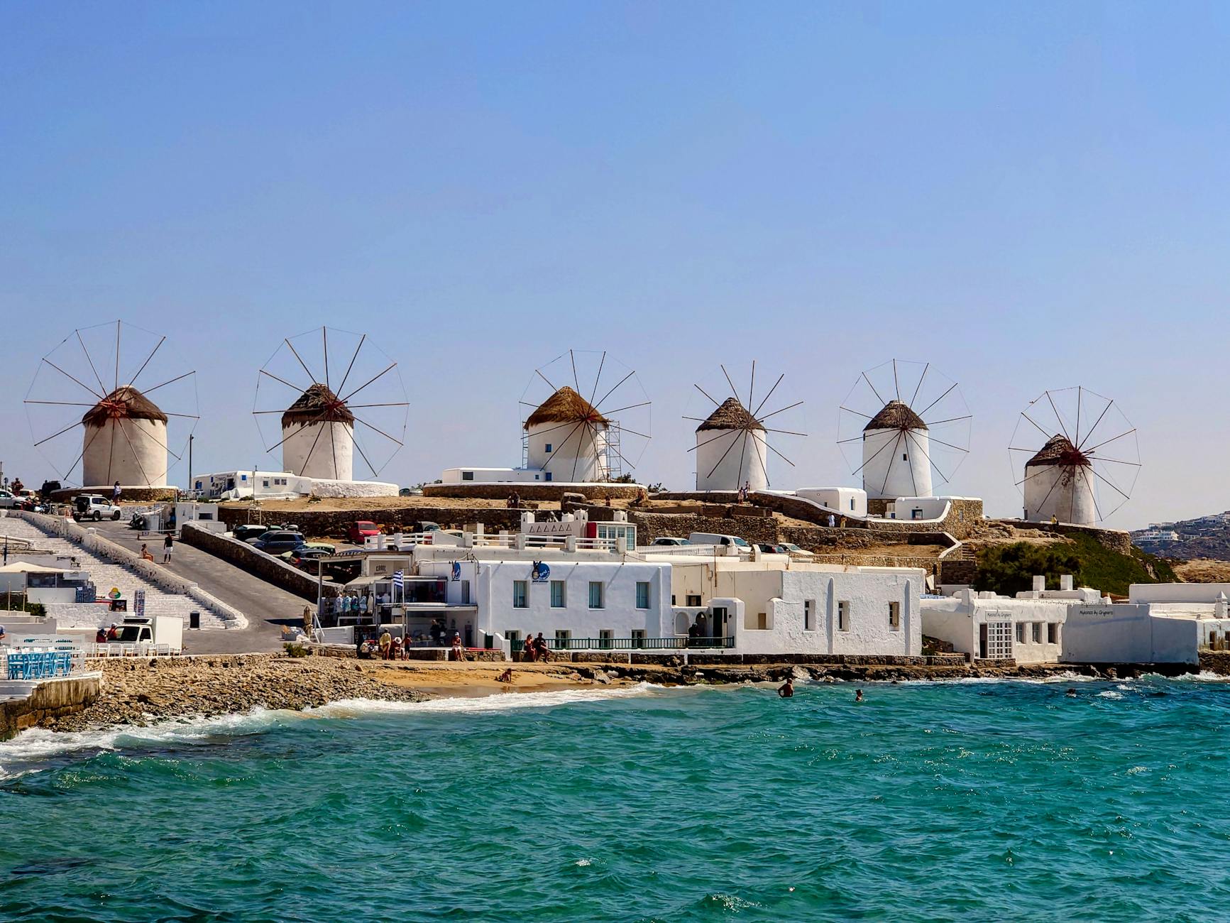 Callejuelas blancas con flores rosas y molinos de viento en Mykonos, Grecia