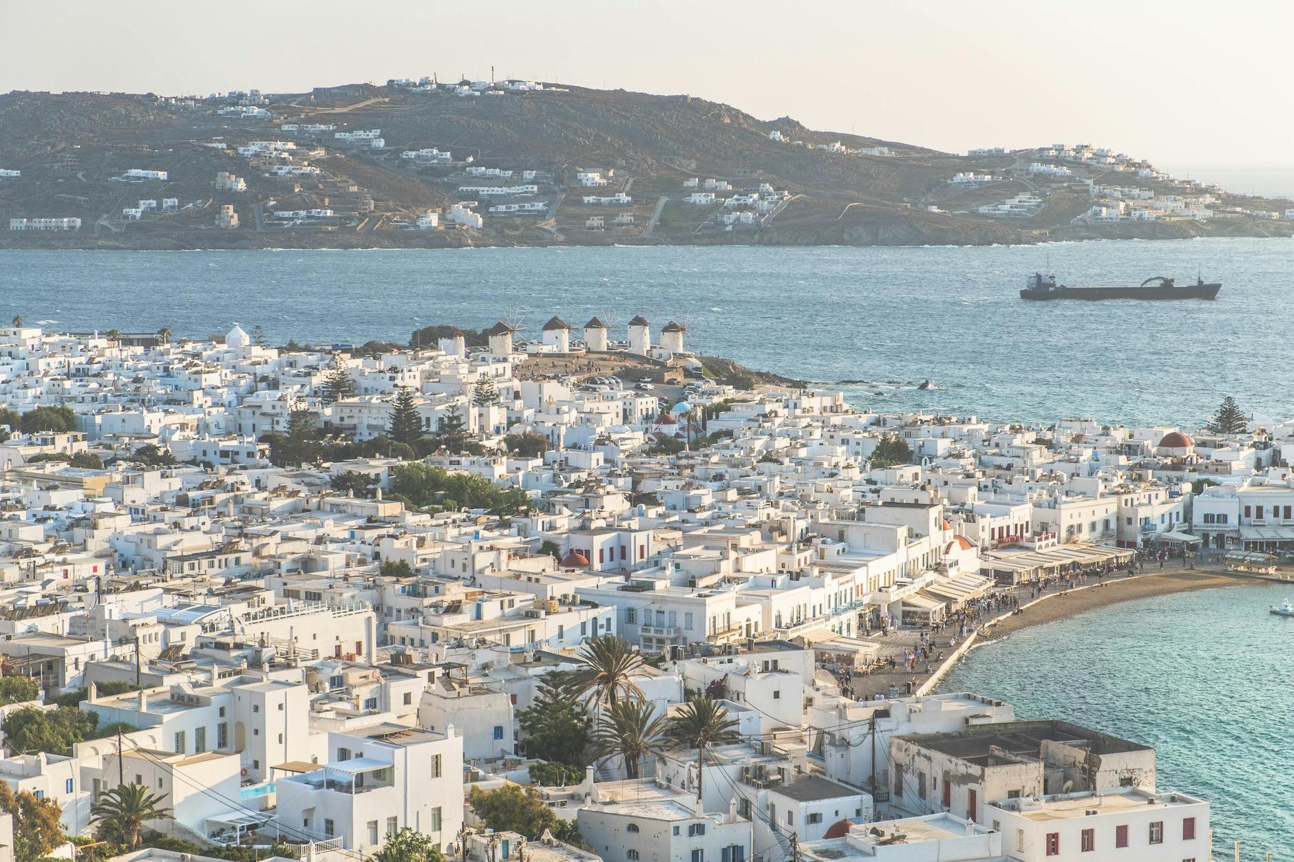 Playa de aguas turquesas en Mykonos con tumbonas y ambiente animado