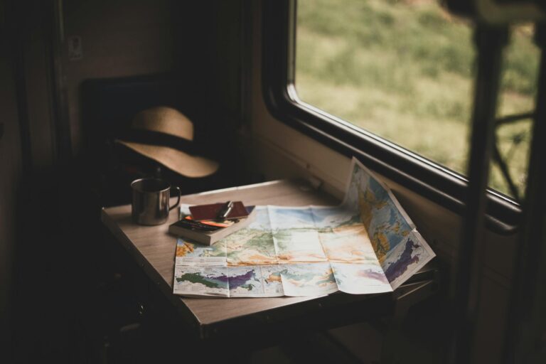 Manos de mujer sobre un mapa abierto con un cuaderno de notas y café