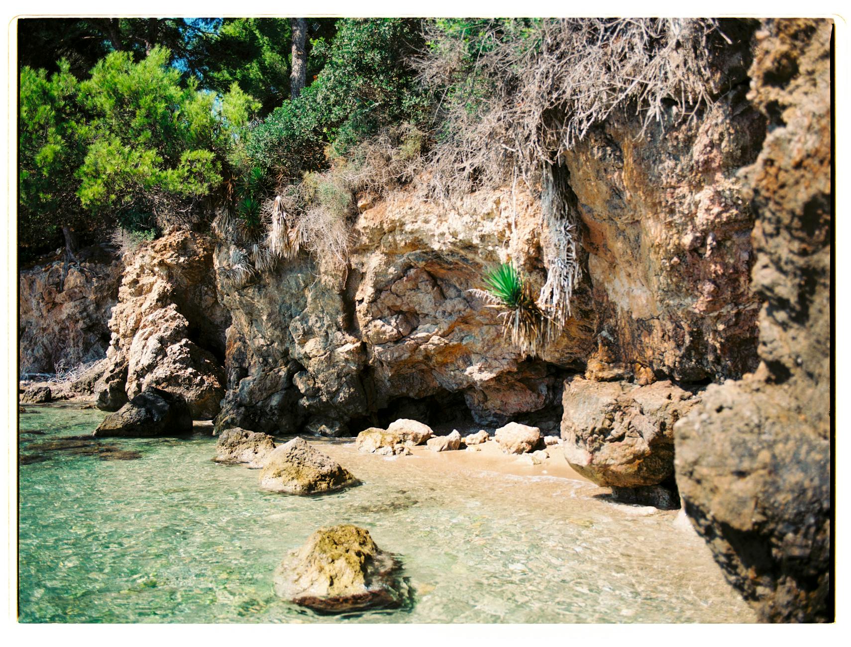 Cala de aguas turquesas rodeada de pinos y acantilados en Mallorca