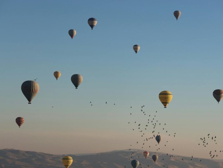 Decenas de globos aerostáticos de colores sobrevolando las formaciones rocosas de Capadocia al amanecer