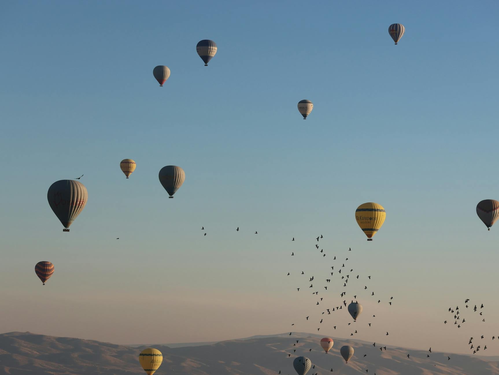 Decenas de globos aerostáticos de colores sobrevolando las formaciones rocosas de Capadocia al amanecer