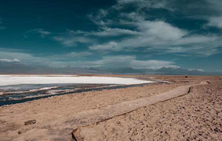 Paisaje rojizo del desierto de Atacama con volcanes al fondo al atardecer