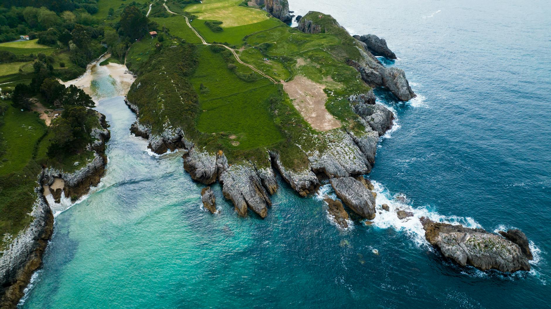 Playa virgen del norte de Asturias con acantilados verdes y mar bravo