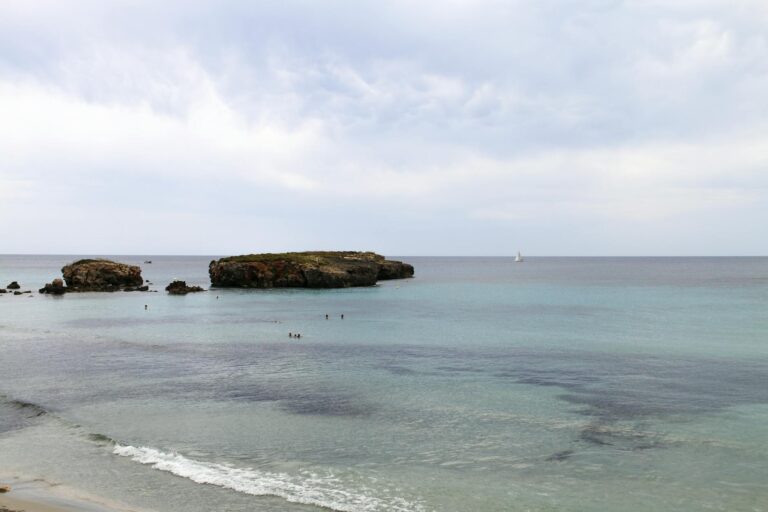 Aguas turquesas de Cala Macarella en Menorca con vegetación mediterránea