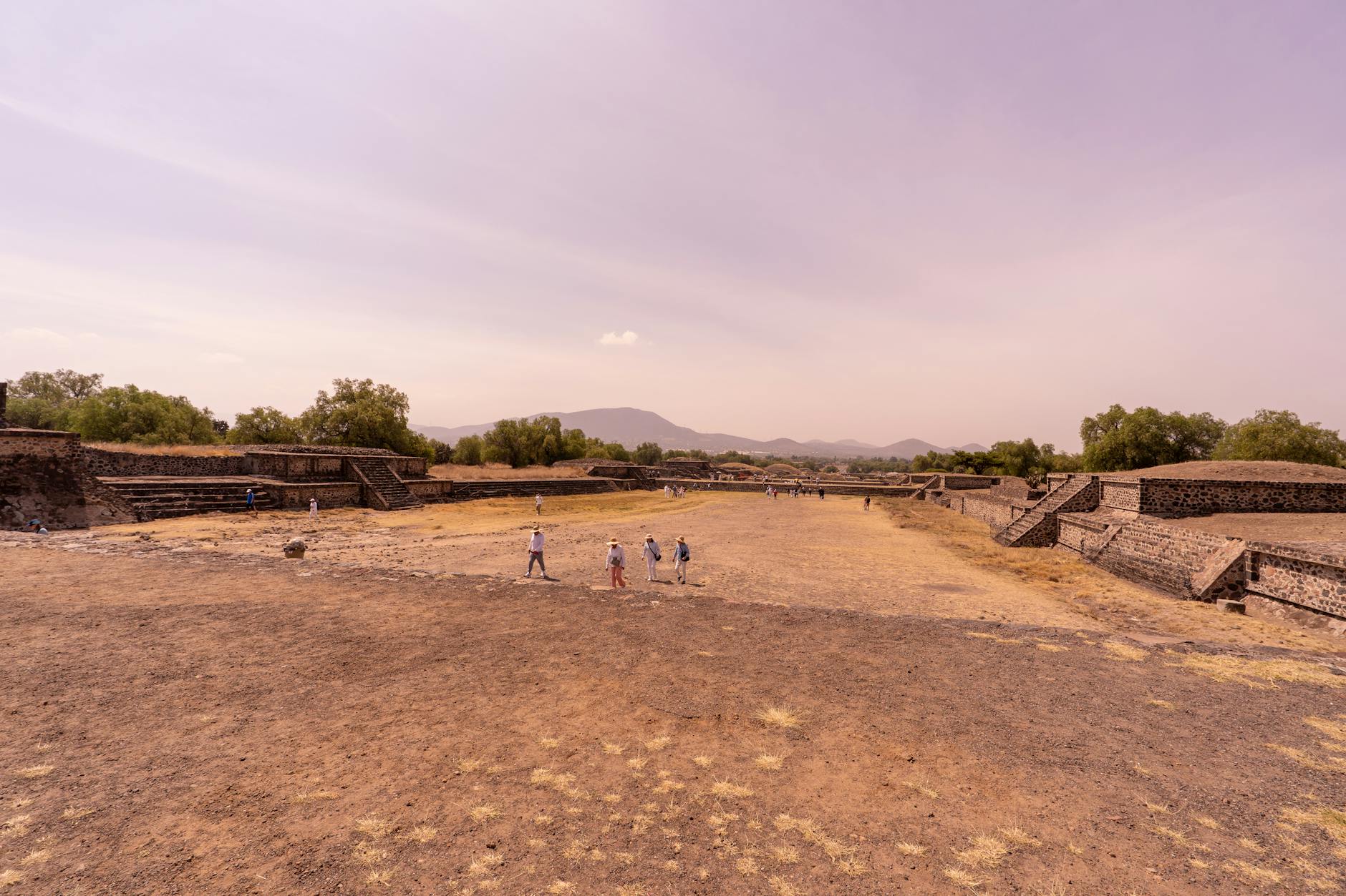 Pirámide del Sol de Teotihuacán con cielo anaranjado al amanecer y pocos turistas