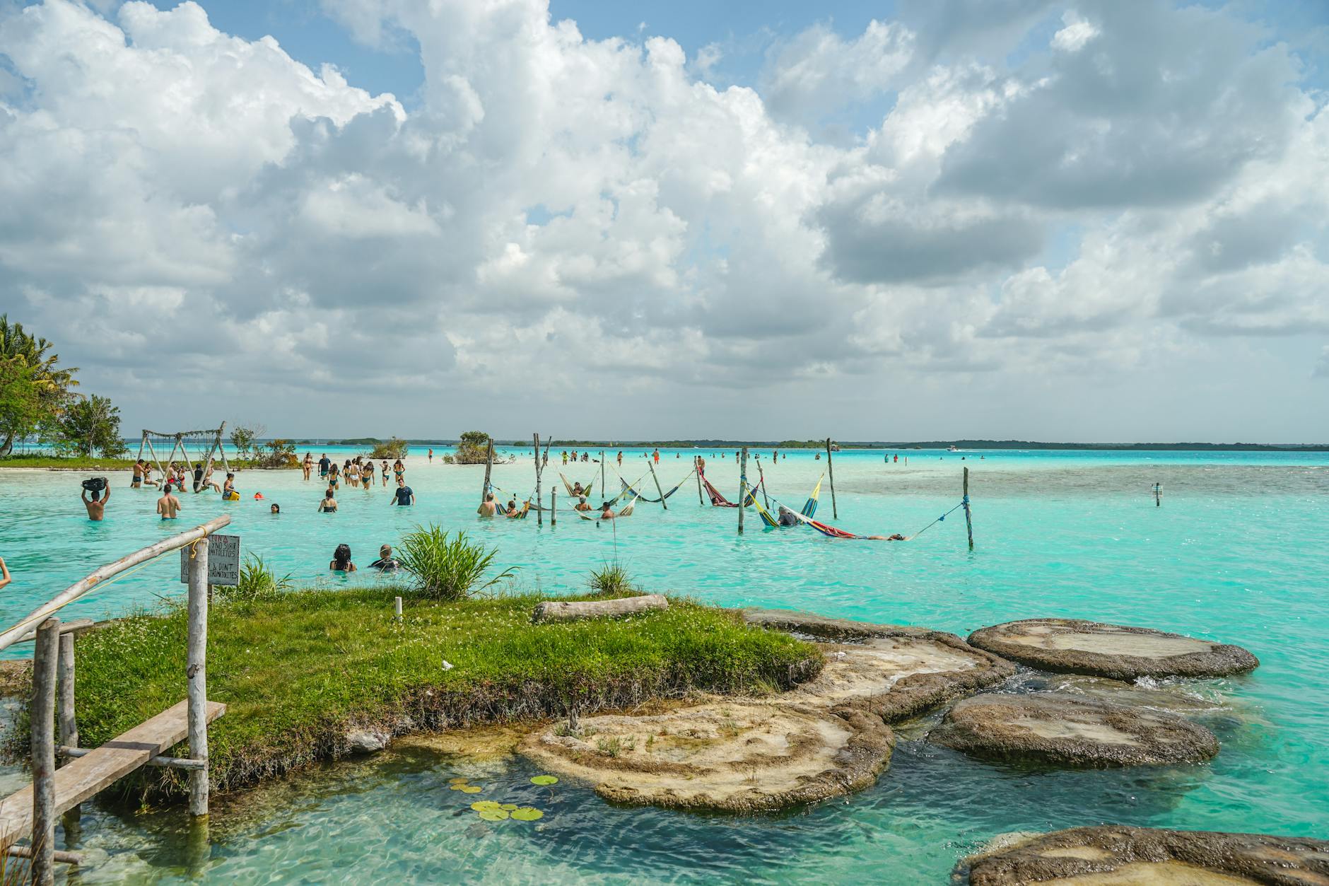 Pequeña embarcación tradicional navegando en las aguas azules de Bacalar con el cielo anaranjado al fondo