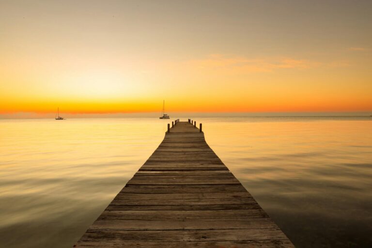 Muelle de madera en Caye Caulker con el mar turquesa al atardecer en Belice