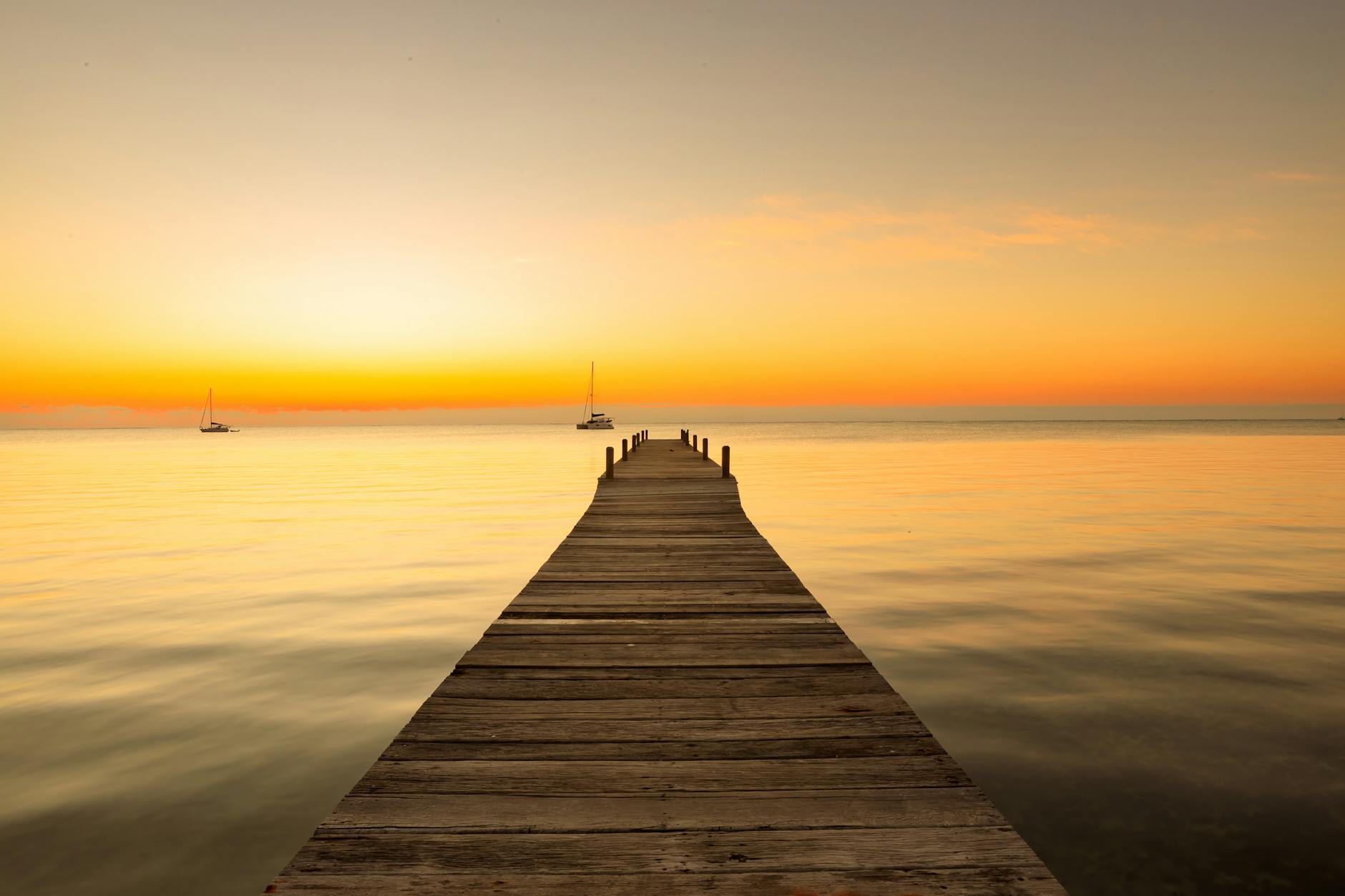 Muelle de madera en Caye Caulker con el mar turquesa al atardecer en Belice